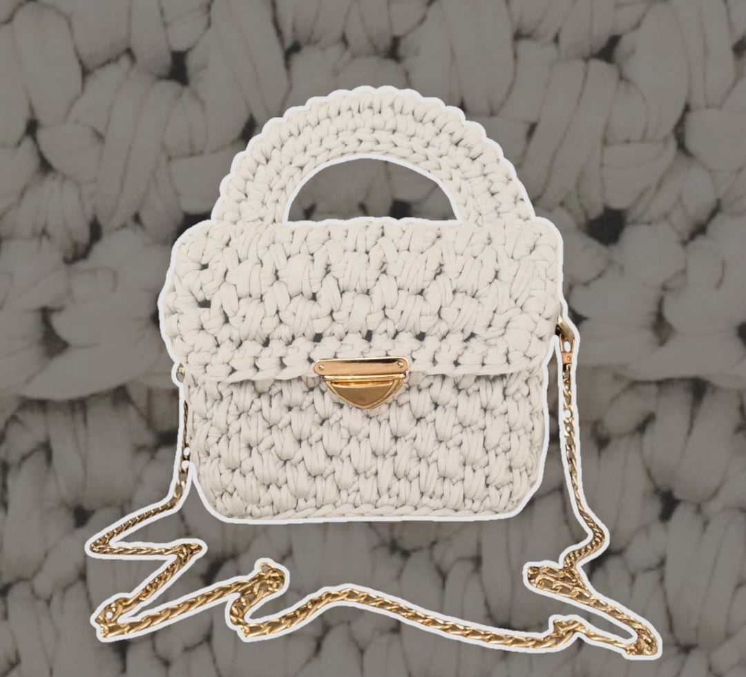 Beige crochet handbag. The details are gold. The bag has a handle on top